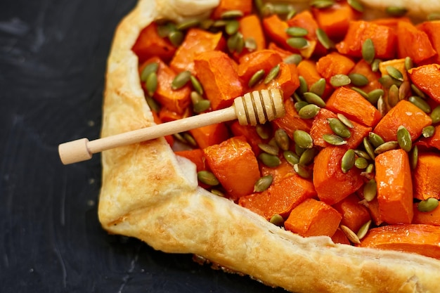 Délicieuse tarte à la citrouille ouverte sur fond noir avec du miel et du thym