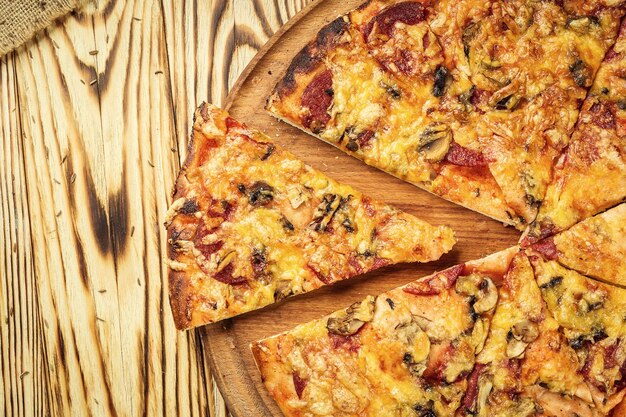 Délicieuse tranche de pizza maison chaude avec du fromage fondant sur une table en bois rustique prête à manger