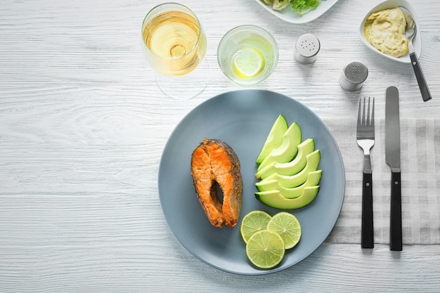 Délicieuse truite arc-en-ciel frite avec citron vert et sauce à l'avocat sur la vue de dessus de table en bois