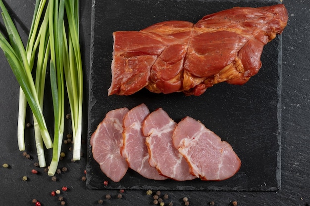 Délicieuse viande fumée de bacon tranché à la main sur un fond sombre le concept de viande