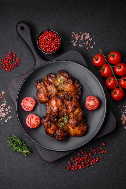 Délicieuse viande de poulet cuite au four avec des épices et des herbes salées sur un fond de béton foncé