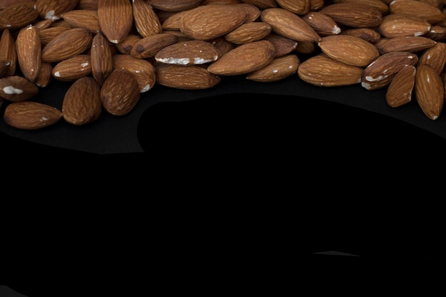 De délicieuses amandes douces grillées se trouvent dans un gros tas de noix d'amandes douces en gros plan avec un fond noir