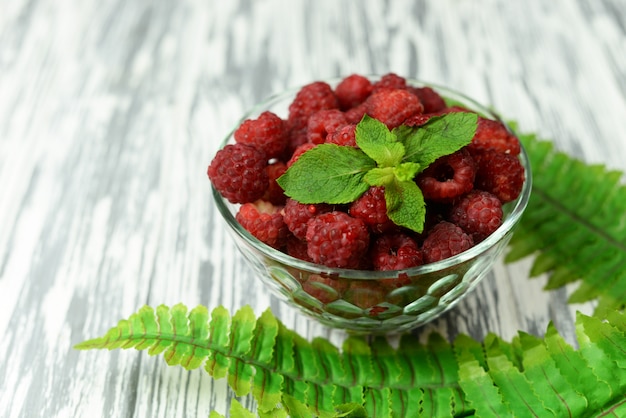 Délicieuses baies framboises en tige sur un fond en bois