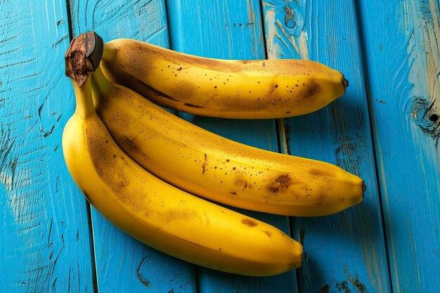 Photo de délicieuses bananes jaunes sur une table en bois bleu.