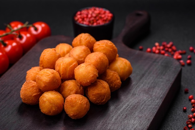 Délicieuses boules de pommes de terre frites avec des épices et des herbes salées de mozzarella sur un fond en béton sombre