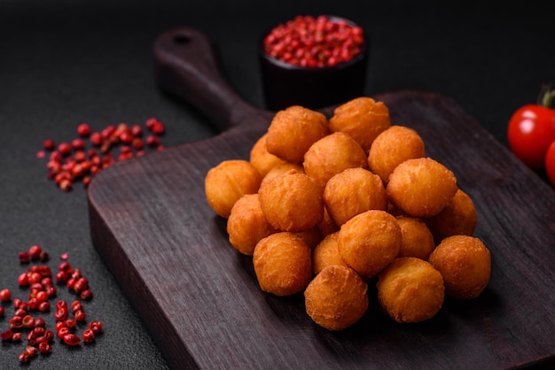 Délicieuses boules de pommes de terre frites avec des épices et des herbes salées de mozzarella sur un fond en béton sombre