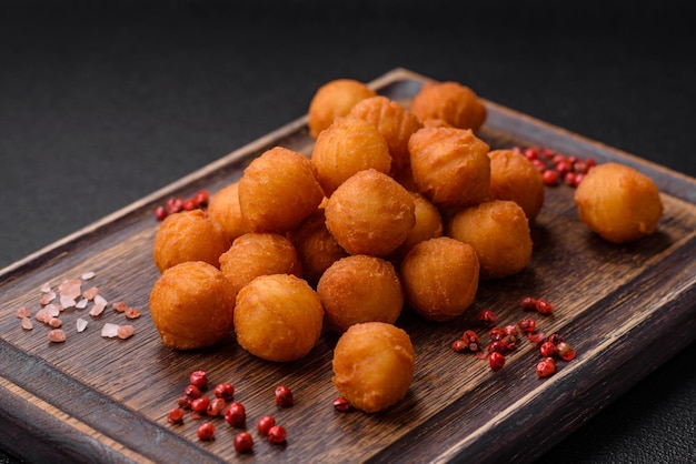 Délicieuses boules de pommes de terre frites avec des épices et des herbes salées de mozzarella sur un fond en béton sombre