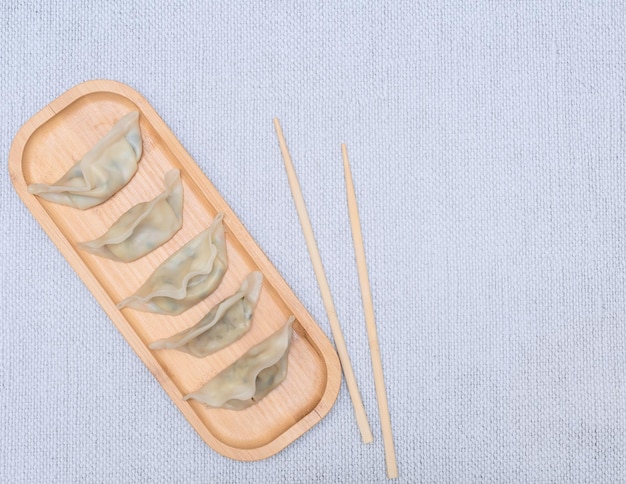 Délicieuses boulettes asiatiques sur une plaque en bois avec des baguettes sur fond gris Mise au point sélective Concept de cuisine asiatique