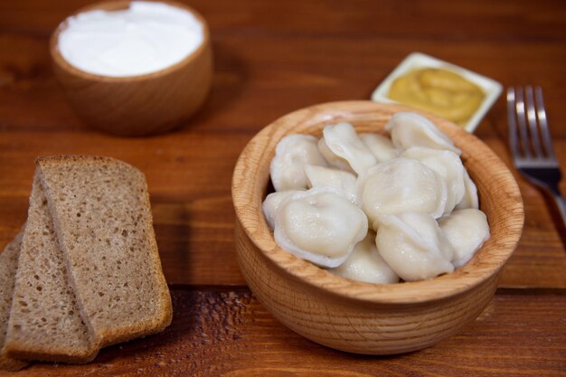 De délicieuses boulettes dans une assiette en bois sont sur la table à côté de la moutarde à la crème sure et du pain