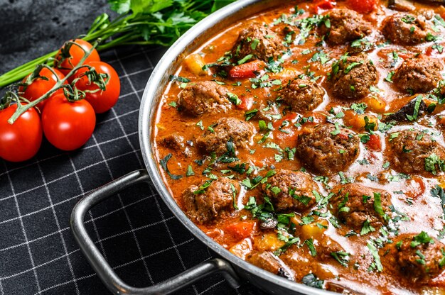 De délicieuses boulettes de viande à base de boeuf haché à la sauce tomate, servies dans une vieille poêle en métal. Surface noire. Vue de dessus