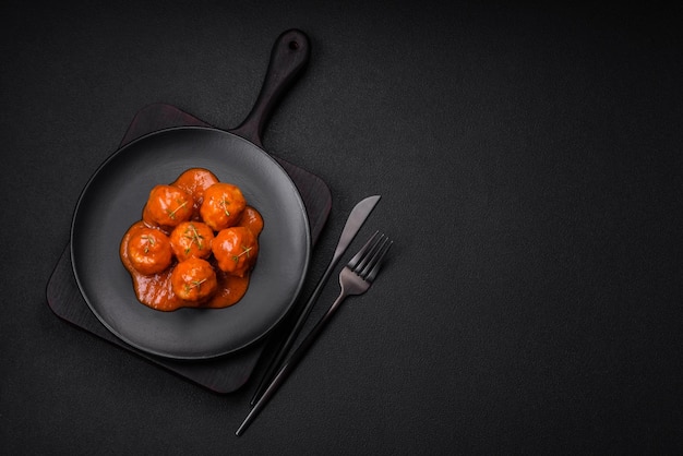 De délicieuses boulettes de viande fraîches à la sauce tomate avec des épices et des herbes salées sur un fond de béton foncé