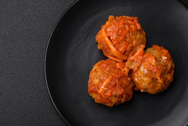 Délicieuses boulettes de viande fraîches de viande hachée ou de poisson avec sauce tomate carottes oignons sel et épices sur fond de béton foncé