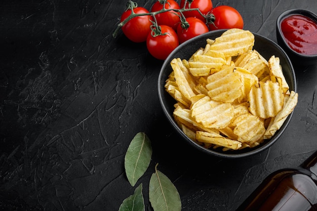 Délicieuses chips de pommes de terre croustillantes sur fond de pierre noire avec espace de copie pour le texte