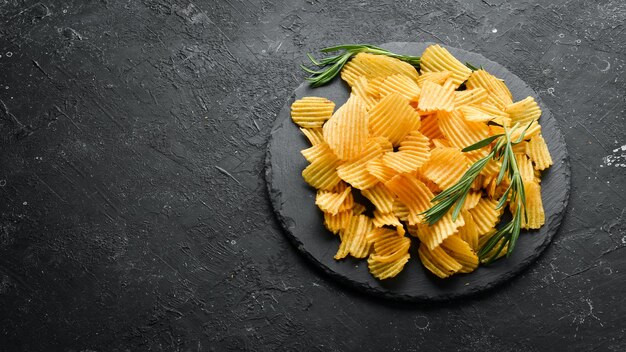 De délicieuses chips de pommes de terre salées Des collations à la bière sur fond de pierre noire Vue de dessus Espace libre pour votre texte