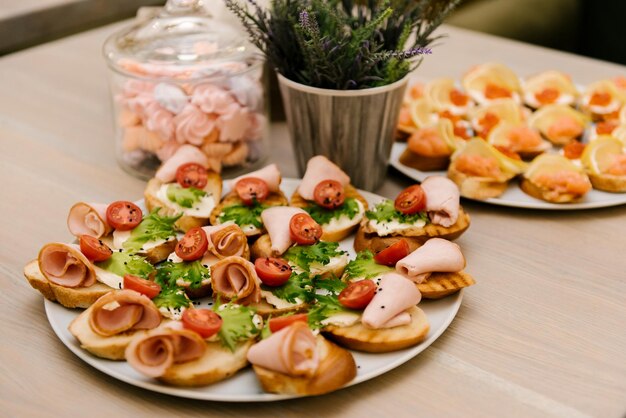 Délicieuses collations italiennes à la tomate épicée ou bruschetta sur des tranches de baguette grillée décorées de jambon de poisson rouge au basilic sur une planche de bois