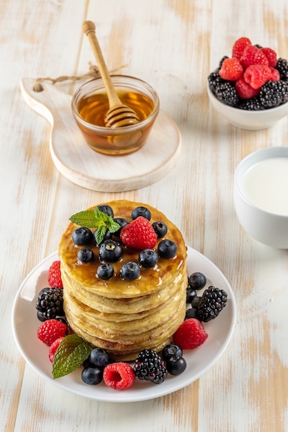 Délicieuses crêpes aux baies fraîches sur table en bois blanc.