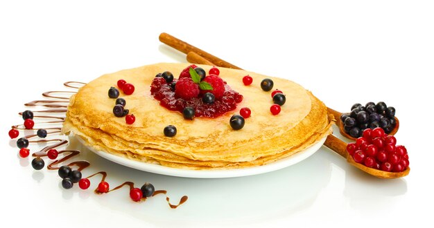 Délicieuses crêpes aux fruits rouges et confiture sur plaque isolated on white