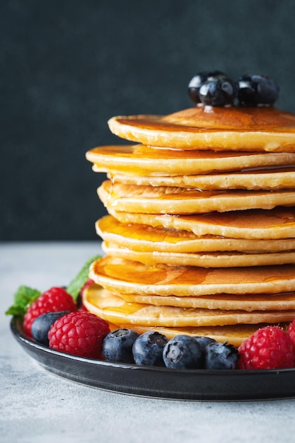 Délicieuses crêpes aux myrtilles fraîches framboise et sirop d'érable ou miel sur fond sombre