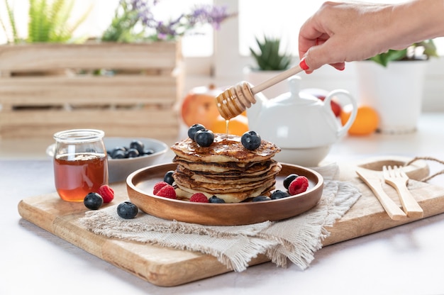 Délicieuses crêpes aux myrtilles fraîches, framboises et miel sur une assiette