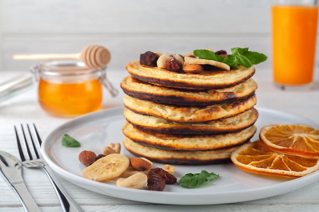 De délicieuses crêpes fraîches avec des bananes séchées, des oranges, des noix et du miel sur une assiette