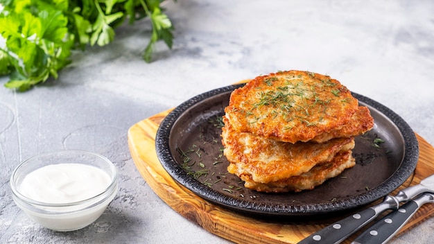 Délicieuses crêpes de pommes de terre sur une poêle à frire avec de la crème sure