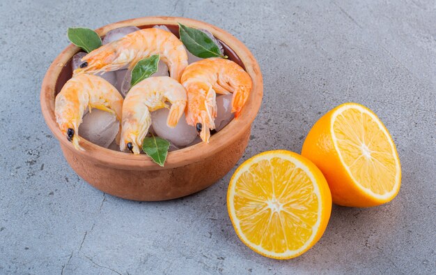 Délicieuses crevettes dans la glace avec des feuilles de laurier dans un bol d'argile sur un fond de pierre.