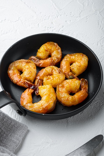 Photo délicieuses crevettes sautées avec assaisonnement cajun, curry et lime, sur une poêle à frire, sur blanc