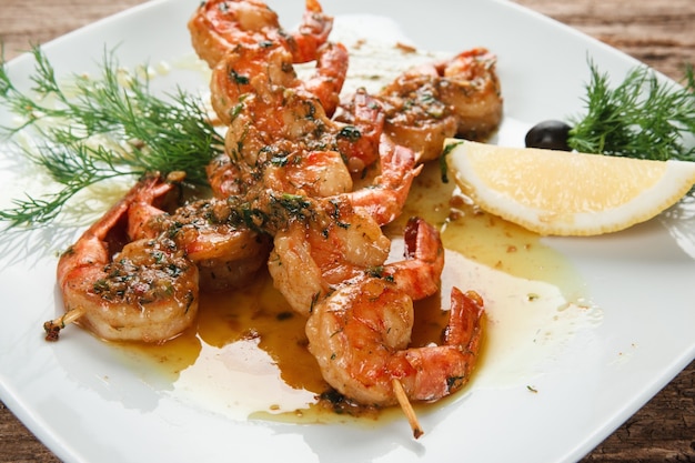 Photo de délicieuses crevettes servies avec des herbes et du citron sur une plaque blanche en vue rapprochée. photo des menus.