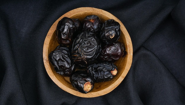 Délicieuses dates ajwa kurma nabi ou dates du prophète Kurma Ajwa sur la texture du tissu noir