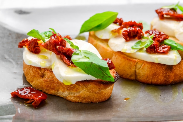 Délicieuses entrées italiennes savoureuses, ou bruschetta, sur des tranches de baguette grillée garnies de basilic