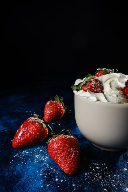 Photo délicieuses fraises sur une base texturée bleue avec un fond sombre