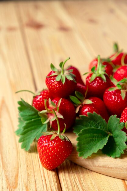 Délicieuses fraises juteuses sur planche de bois sur fond de bois Récolte de fraises à la ferme Alimentation saine alimentation crue et concept de nourriture de désintoxication Source naturelle de vitamines et d'antioxydants