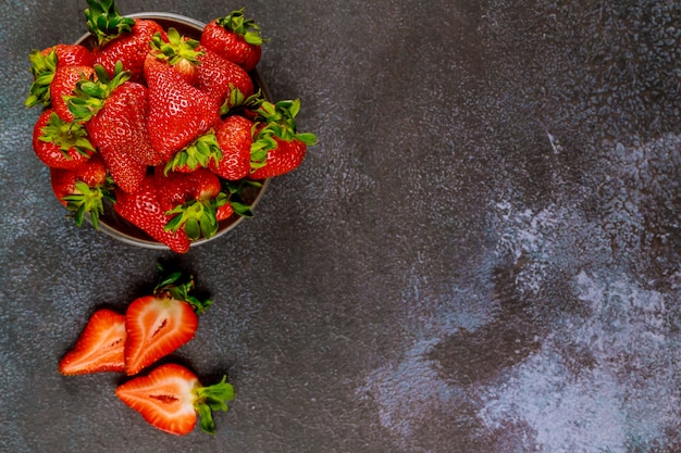 Délicieuses fraises mûres dans une assiette sur une surface grise