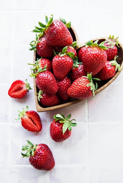 De délicieuses fraises mûres fraîches dans un bol en bois en forme de coeur