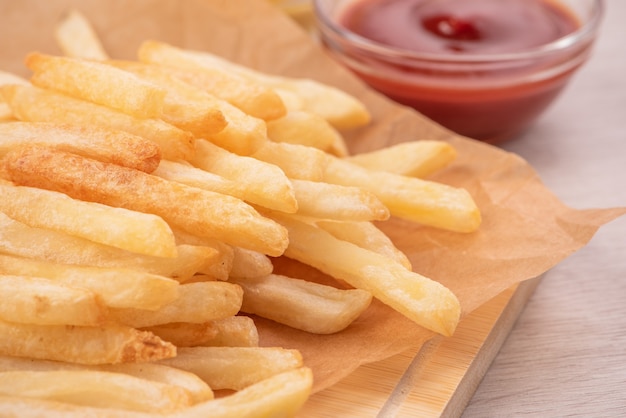 Délicieuses frites dorées sur une plaque à pâtisserie kraft et plateau de service à manger avec du ketchup et de la moutarde jaune, gros plan, style de vie.