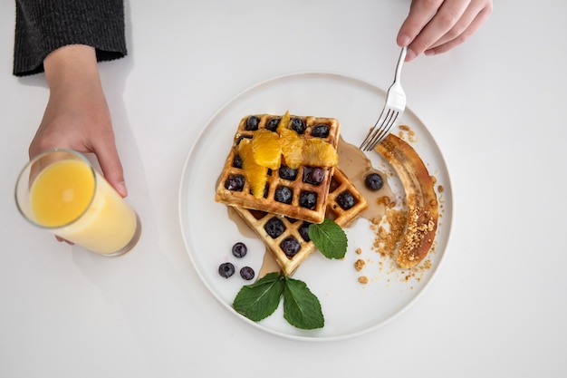 De délicieuses gaufres belges avec des baies et des fruits et un verre de jus