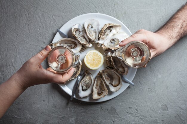 Délicieuses huîtres avec tranche de citron et verres de vin blanc, vue de dessus