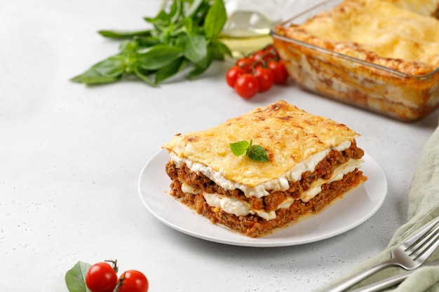 Délicieuses lasagnes avec sauce à la viande bolognaise et fromage sur plaque blanche avec fourchette et couteau