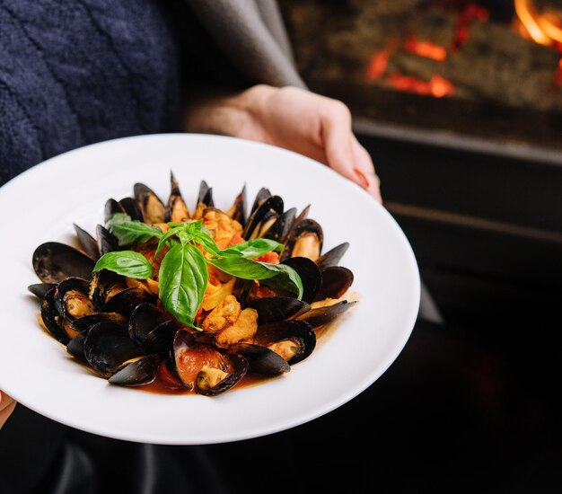 Délicieuses moules fraîches cuites à la vapeur dans une sauce au vin blanc dans une assiette blanche