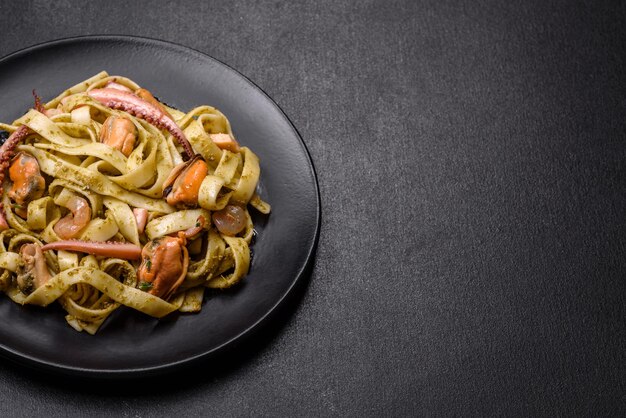 Délicieuses pâtes fraîches au pesto et fruits de mer sur une plaque noire