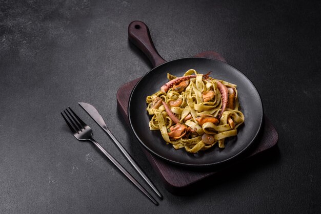 Délicieuses pâtes fraîches au pesto et fruits de mer sur une plaque noire