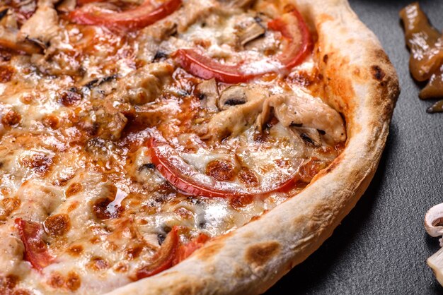 De délicieuses pizzas italiennes fraîches aux champignons et tomates sur fond de béton foncé. cuisine italienne