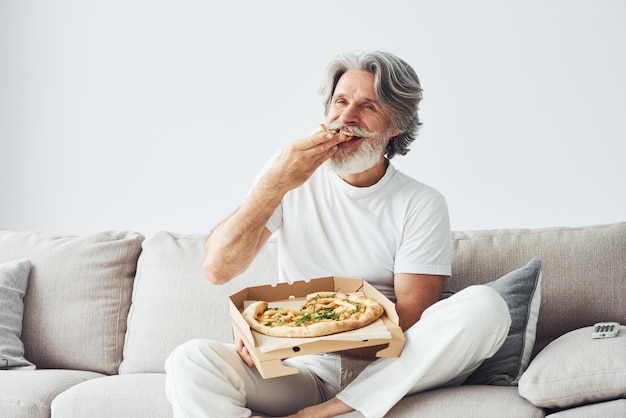 Avec de délicieuses pizzas Montres émission de télévision Homme moderne et élégant aux cheveux gris et à la barbe à l'intérieur