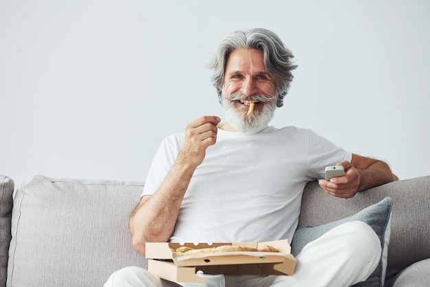 Avec de délicieuses pizzas Montres émission de télévision Homme moderne et élégant aux cheveux gris et à la barbe à l'intérieur