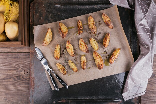 Délicieuses pommes de terre au four aux herbes et sel sur papier parchemin. Dessus