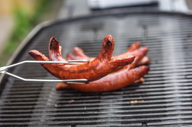 Photo de délicieuses saucisses fumées sur le barbecue du jardin.