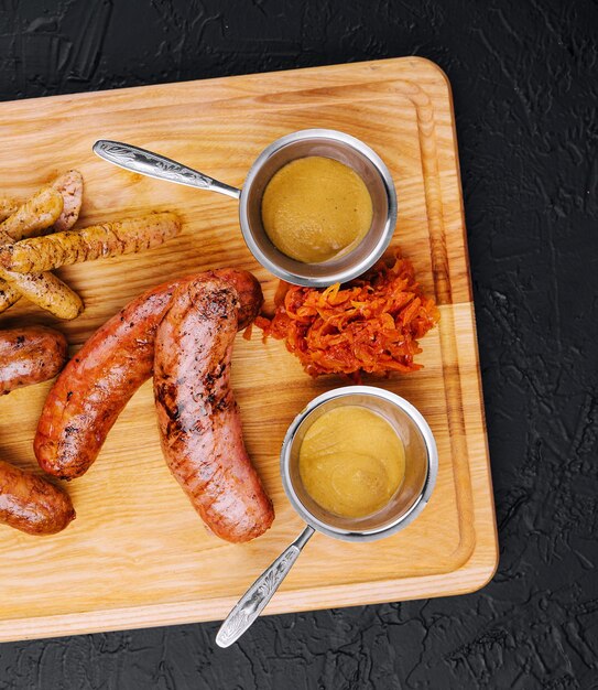 Délicieuses saucisses grillées fraîches sur table en bois