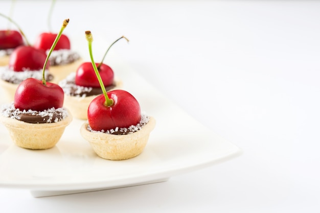 Délicieuses tartelettes au chocolat avec un espace de copie isolé cerise et noix de coco