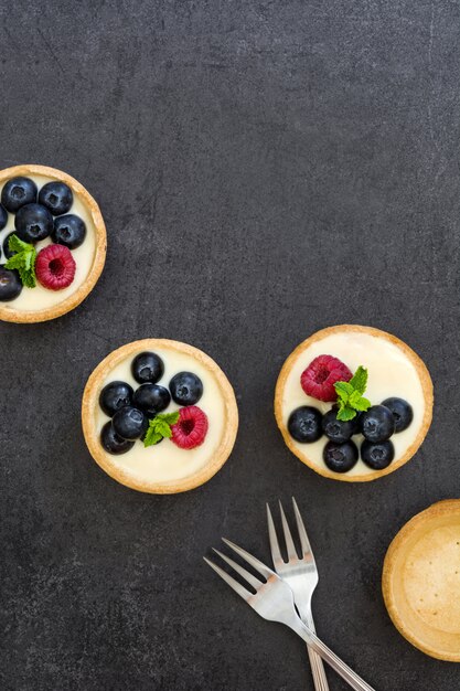 Délicieuses tartelettes aux framboises et bleuets sur fond noir