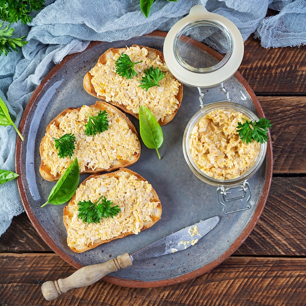 Délicieuses tartines aux rillettes de poulet maison. Snack-sandwich avec pâté de poulet sur fond de bois. Vue de dessus